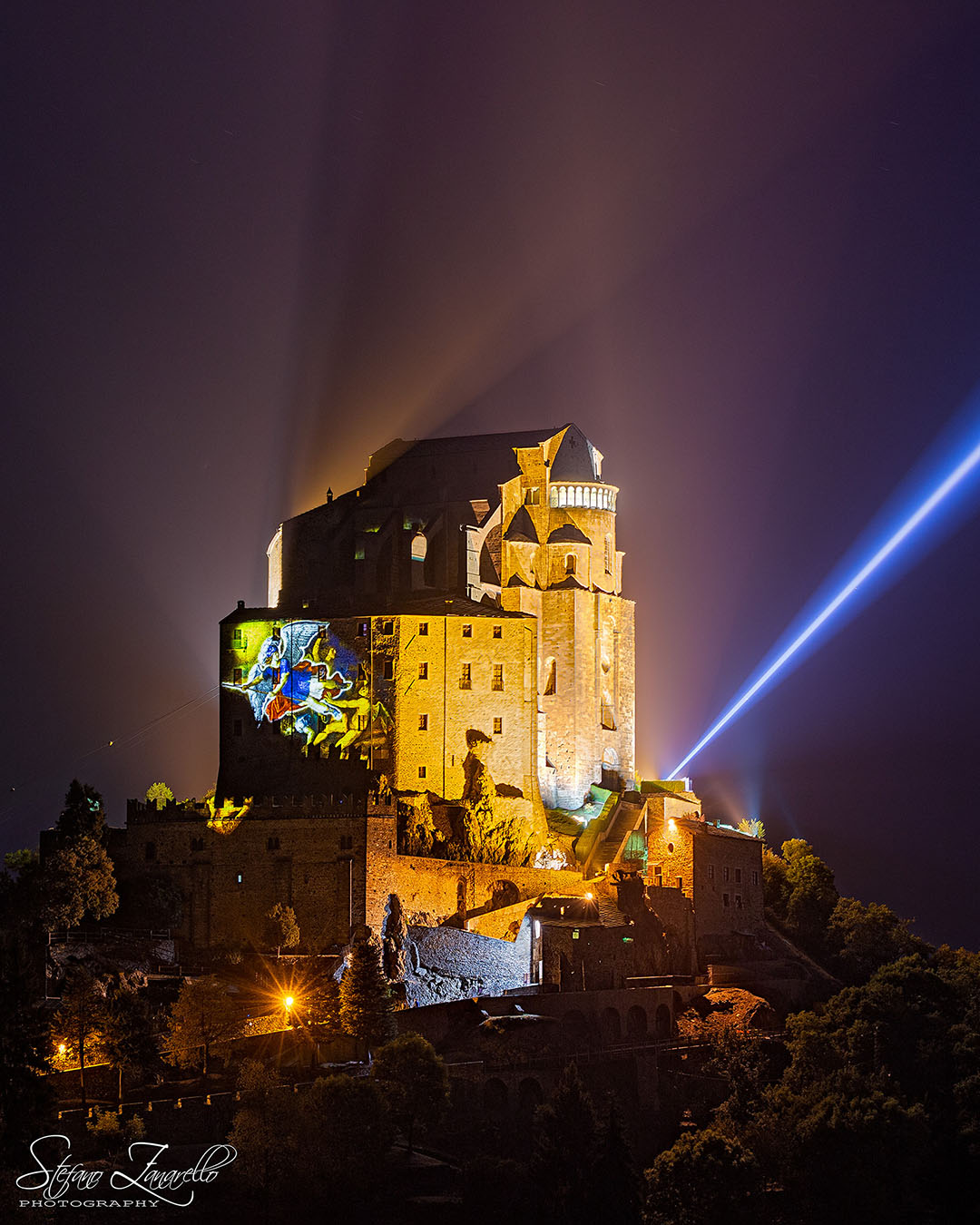 Al calar delle tenebre, la Sacra di San Michele è impreziosita dall'Arcangelo Michele proiettato sulle millenarie mura, mentre la sua spada di luce si proietta alta nel cielo - Stefano Zanarello